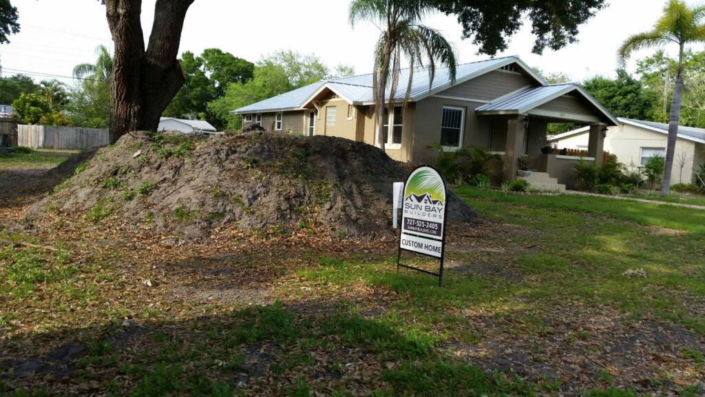 Dirt mound and Sun Bay Builders sign